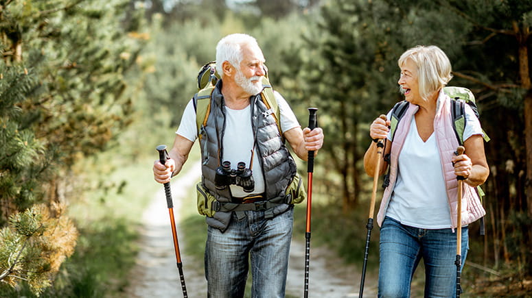 Older couple smiling, laughing, and walking through the woods.